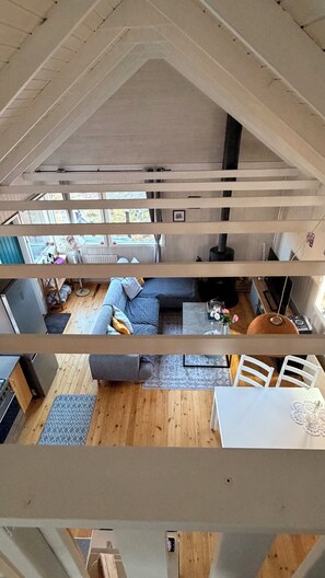Ett loftliknande vardagsrum med högt i tak, en soffa, ett matbord och ett köksområde.