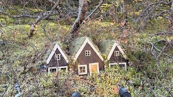 Three small cabins surrounded by dense foliage and a large tree.