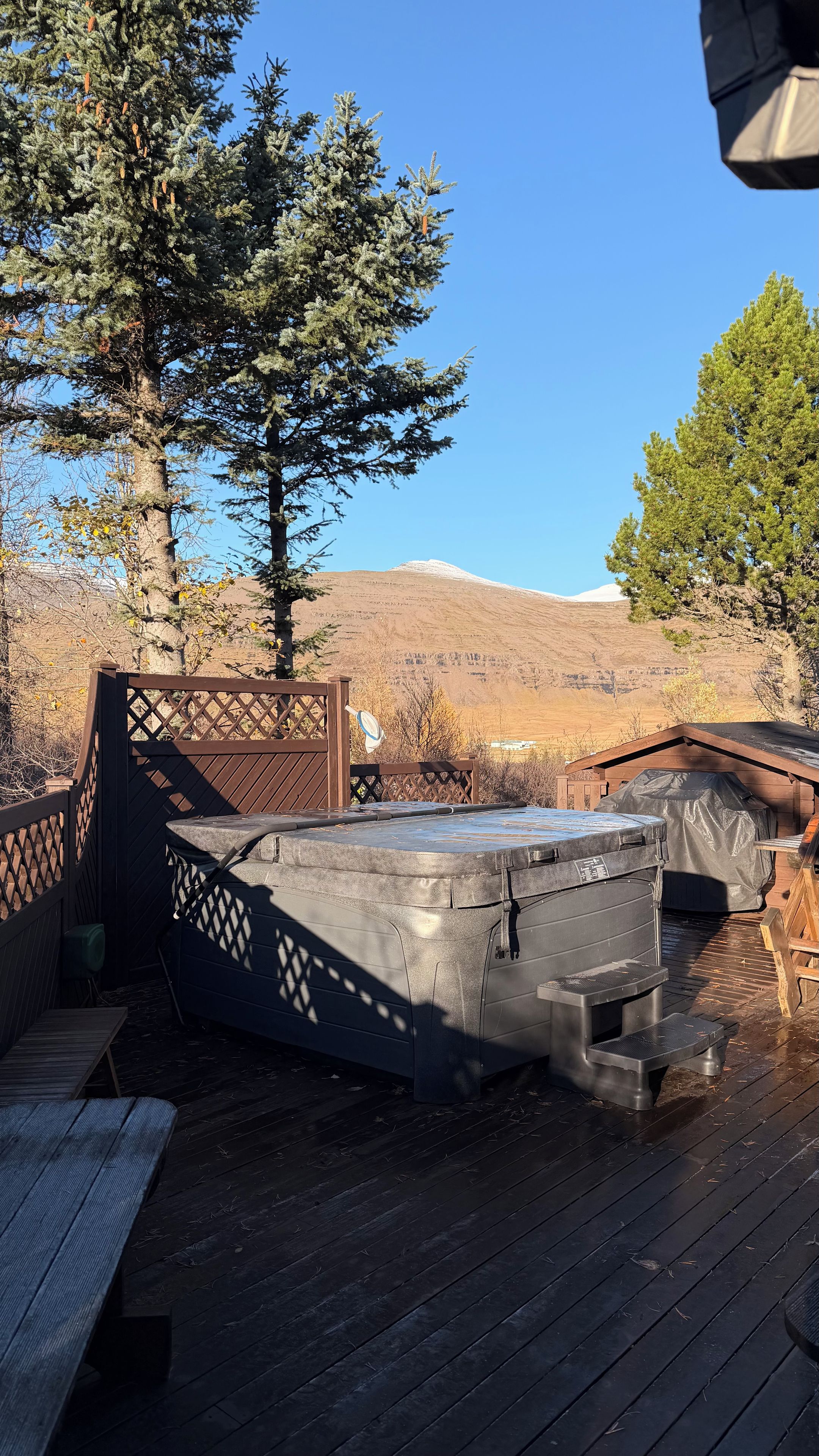 A wooden deck with a hot tub, a picnic table, and a view of a mountain.