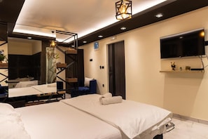 Une chambre d’hôtel moderne équipée d’un grand lit, d’un bureau, d’une chaise, d’un miroir, d’une télévision et d’un escalier.