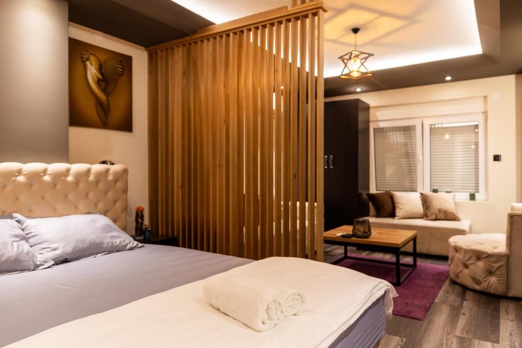 Un dormitorio con una cama grande, un separador de madera, un sofá y una mesa de centro.