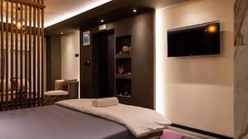 A modern hotel room with a bed, a TV mounted on the wall, and a wooden partition.