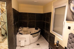 A bathroom with a jacuzzi tub, marble flooring, and a window with blinds. - Vila Salute  (Niš)