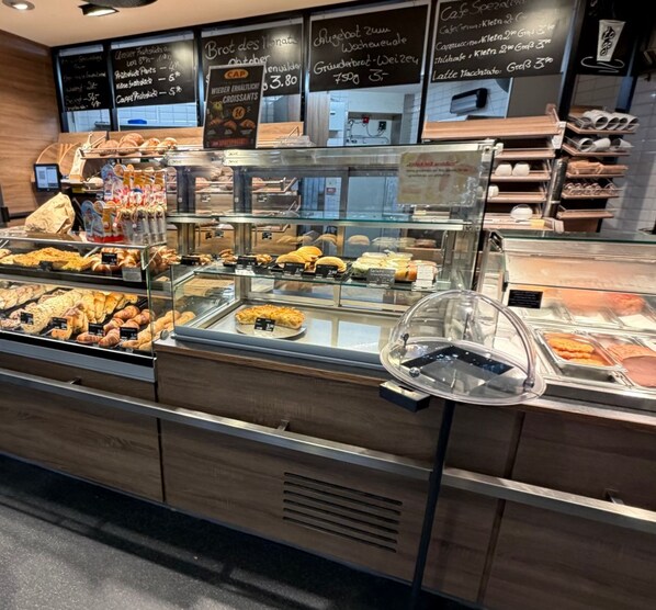 Una vitrina de panadería con diversos productos horneados y un menú en una pizarra.