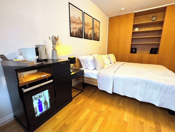 A hotel room with a bed, a desk with a computer, a shelf with decorative items, and framed pictures on the wall. - New Listing (Bad Krozingen)