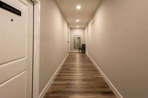 A hallway with a wooden floor, white walls, and a door labeled 'STINGRAY STAY'. - Bluegrass BnB - New, Downtown BG 1 Bedroom Apartment (Bowling Green)