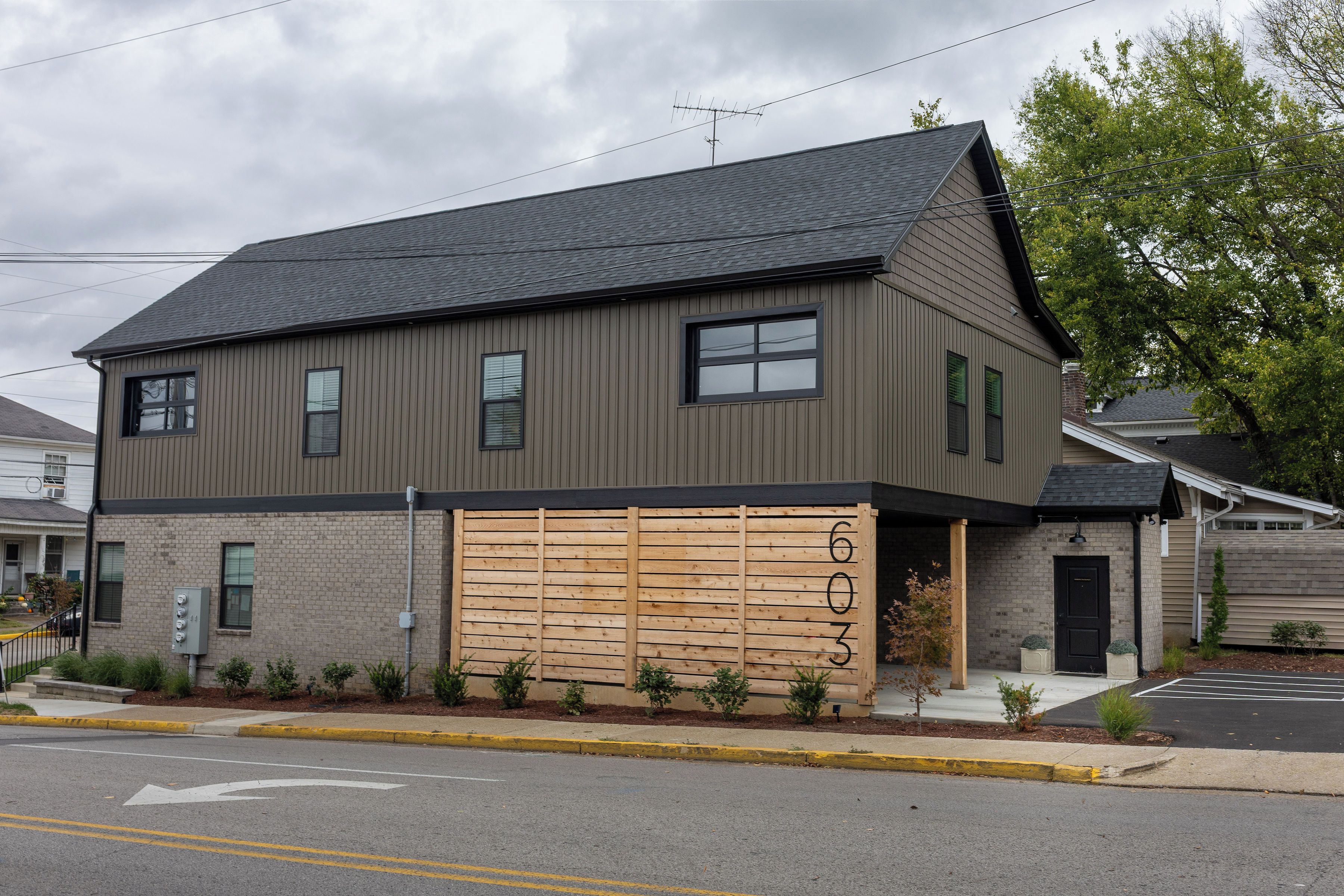 A two-story building with a garage door, a brick facade, and a black roof.