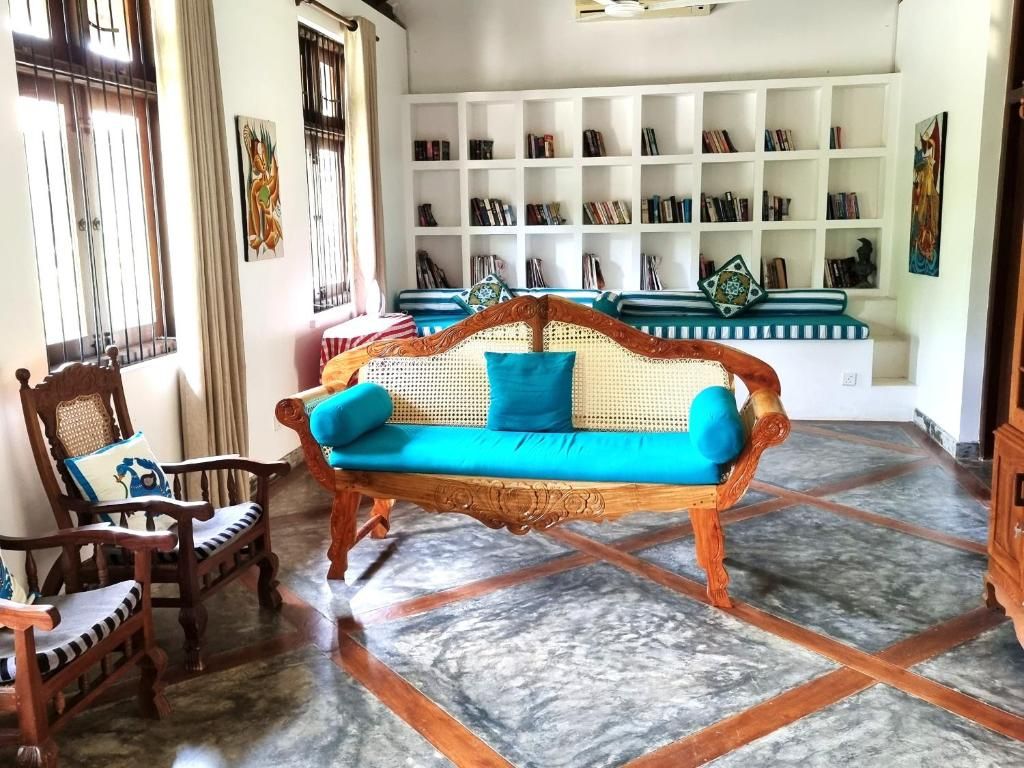Una habitación con un sofá de madera, una silla, una estantería y un suelo con estampado.