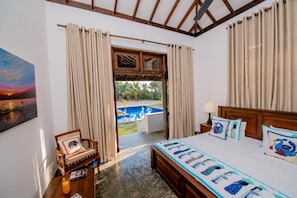 Ein Hotelzimmer mit Bett, Stuhl, Tisch und Blick auf einen Swimmingpool.