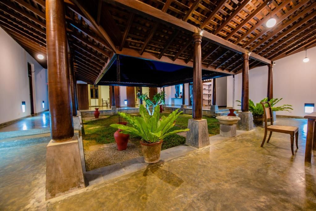 A spacious indoor area with a high ceiling, columns, and potted plants.