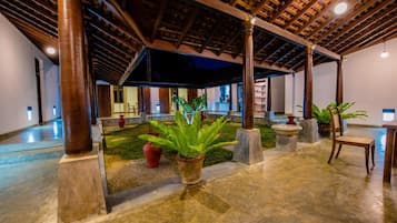 A spacious indoor area with a high ceiling, columns, and potted plants.