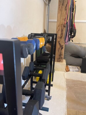 Une salle de sport à domicile équipée d’un banc de développé couché, d’haltères et de bandes de résistance.