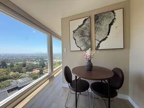 Un coin repas avec une table ronde et quatre chaises, un vase de fleurs et deux tableaux abstraits accrochés au mur.