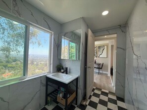 Une salle de bain avec une grande fenêtre, un lavabo et un miroir.