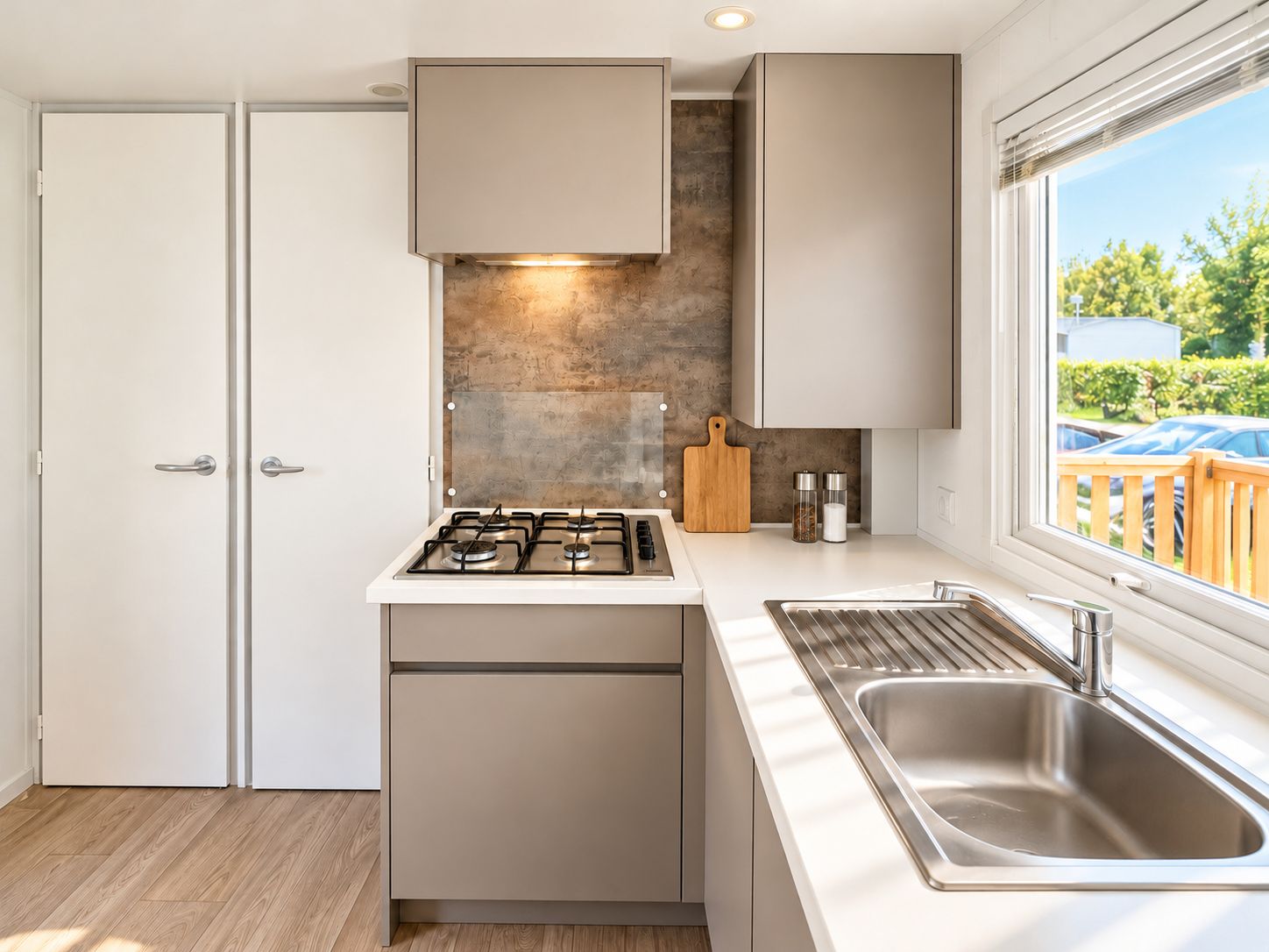 A modern kitchen with a gas stove, a built-in oven, a stainless steel sink, and a window with a view of the outside.