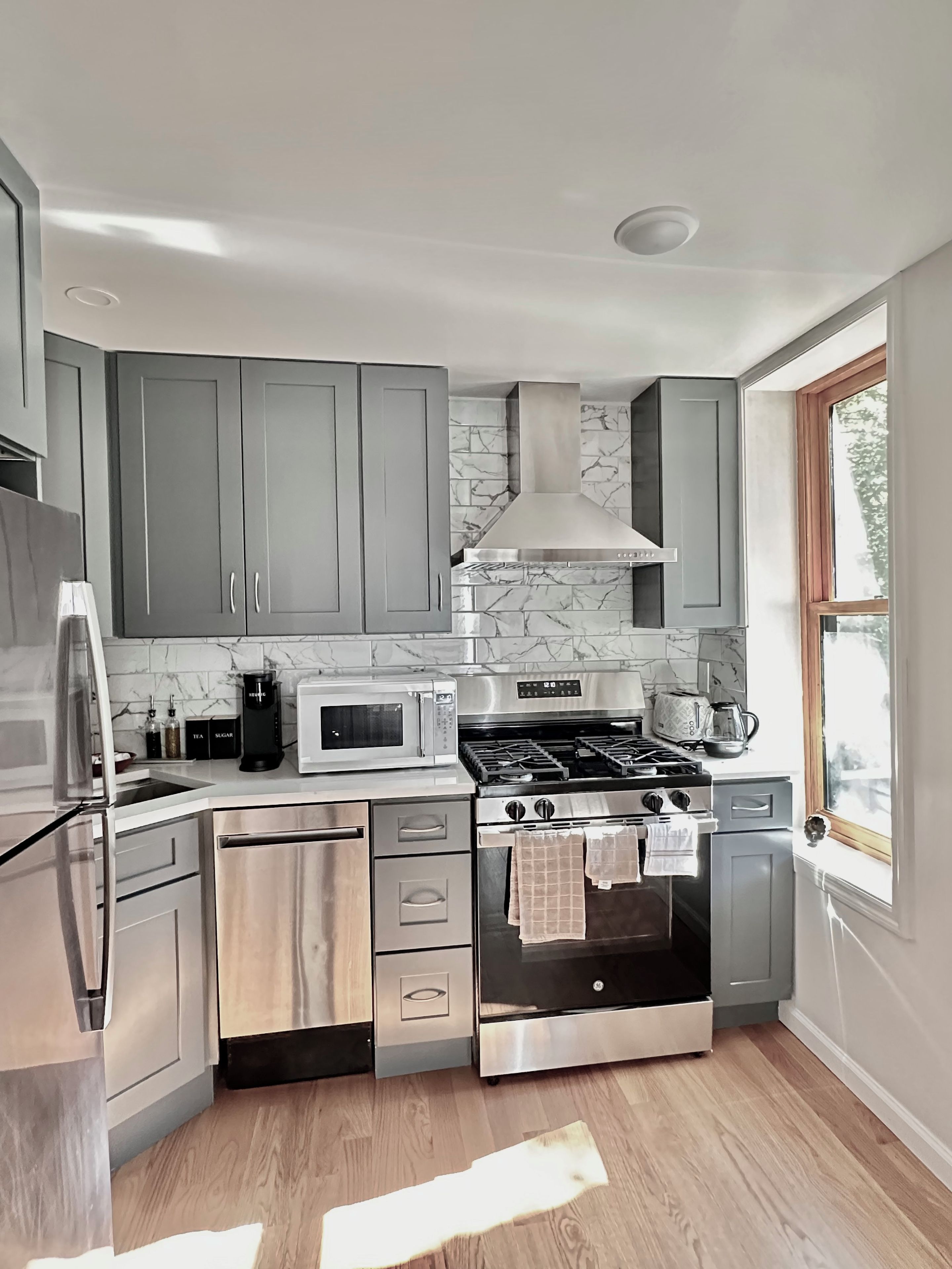 A modern kitchen with grey cabinets, a stainless steel stove, and a microwave.