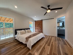 A bedroom with a bed, wooden flooring, a ceiling fan, and a view through a window. - 4BR, 2 Suites & Covered Deck, Edge Of Springfield (Ozark)