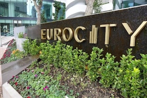 A sign with the words 'EUROCITY' in large letters, surrounded by a landscaped garden with various plants and flowers. - VV -Skyline Large Studio| Pool Gym| City Centre #2 (Gibraltar)