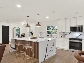 A modern kitchen with a large island, pendant lighting, and white cabinetry. - Casa Selva (Orlando)
