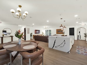 Una cocina moderna con una isla central, suelo de madera e iluminación colgante.