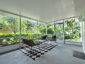 A covered patio with a checkered floor, two wicker chairs, and a table. - Casa Selva (Orlando)