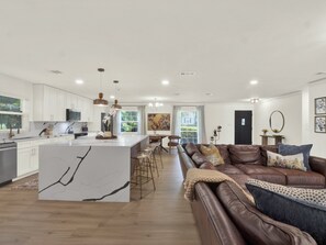 Una cocina moderna con armarios blancos, una isla de mármol e iluminación colgante.