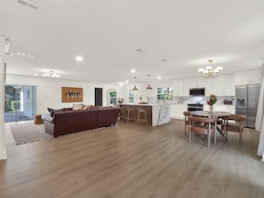 A spacious living area with a brown sofa, a dining table with chairs, and a kitchen with white cabinets and stainless steel appliances. - Casa Selva (Orlando)