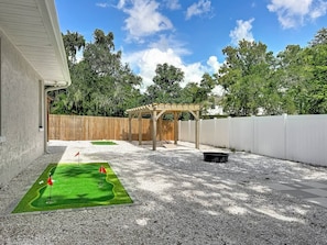 En baghave med et lille putting green, en træpergola og et hvidt hegn.