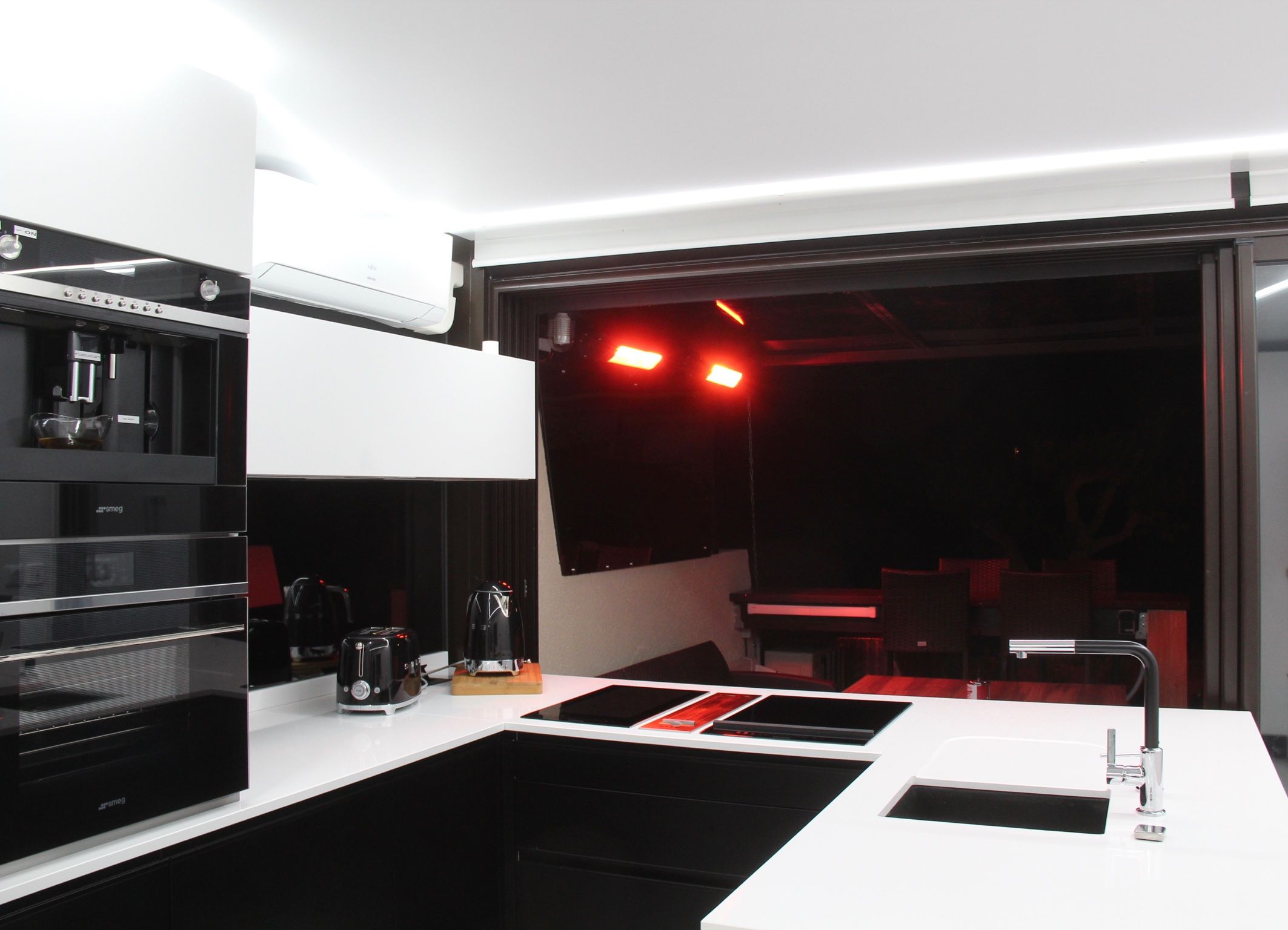 Una cocina moderna con cafetera espresso integrada, un tostador y un lavamanos.