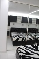 Une chambre à coucher avec une armoire à miroir, une couvre-lit à motifs zébrés et une tête de lit noire.
