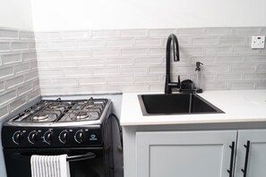 A kitchen with a gas stove, a black faucet, and a white countertop. - Solara Boho West End Negril Stay (Negril)