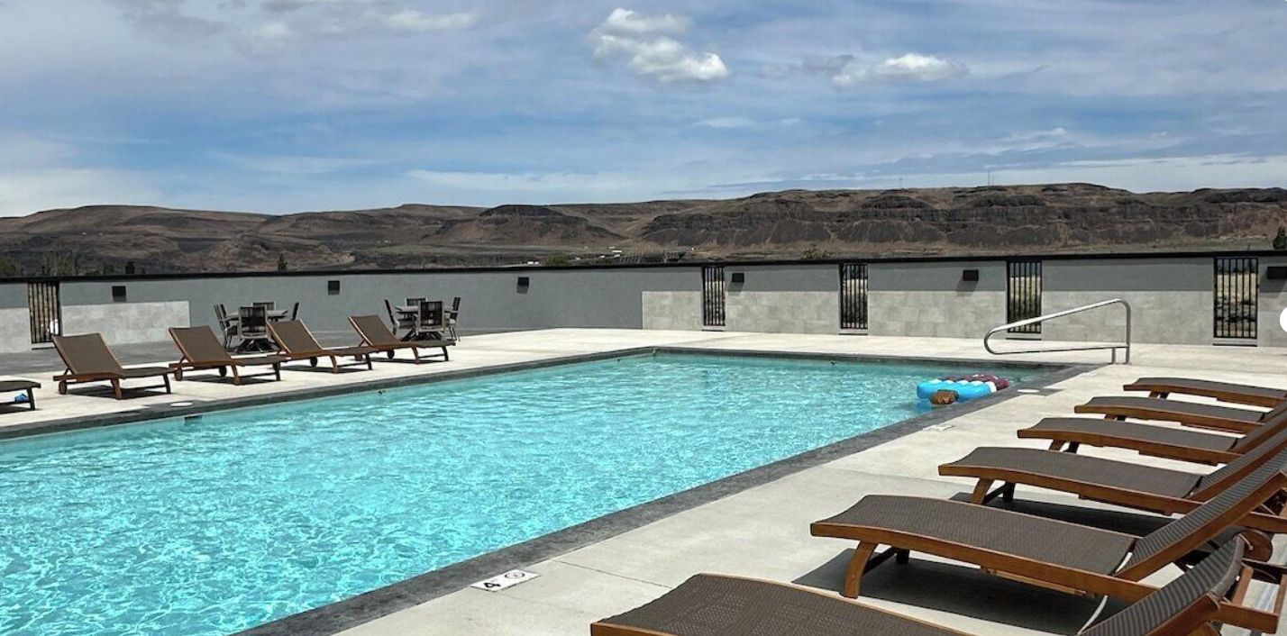 A swimming pool with lounge chairs and a view of a hilly landscape.