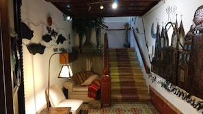 Una stanza accogliente con un divano, una lampada, un tappeto decorato e una scala che conduce a un balcone.