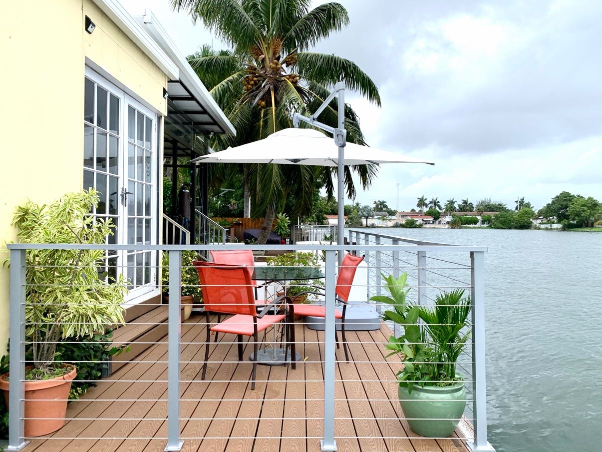Eine Terrasse mit Sitzgelegenheiten, einem Geländer und Blick aufs Wasser.