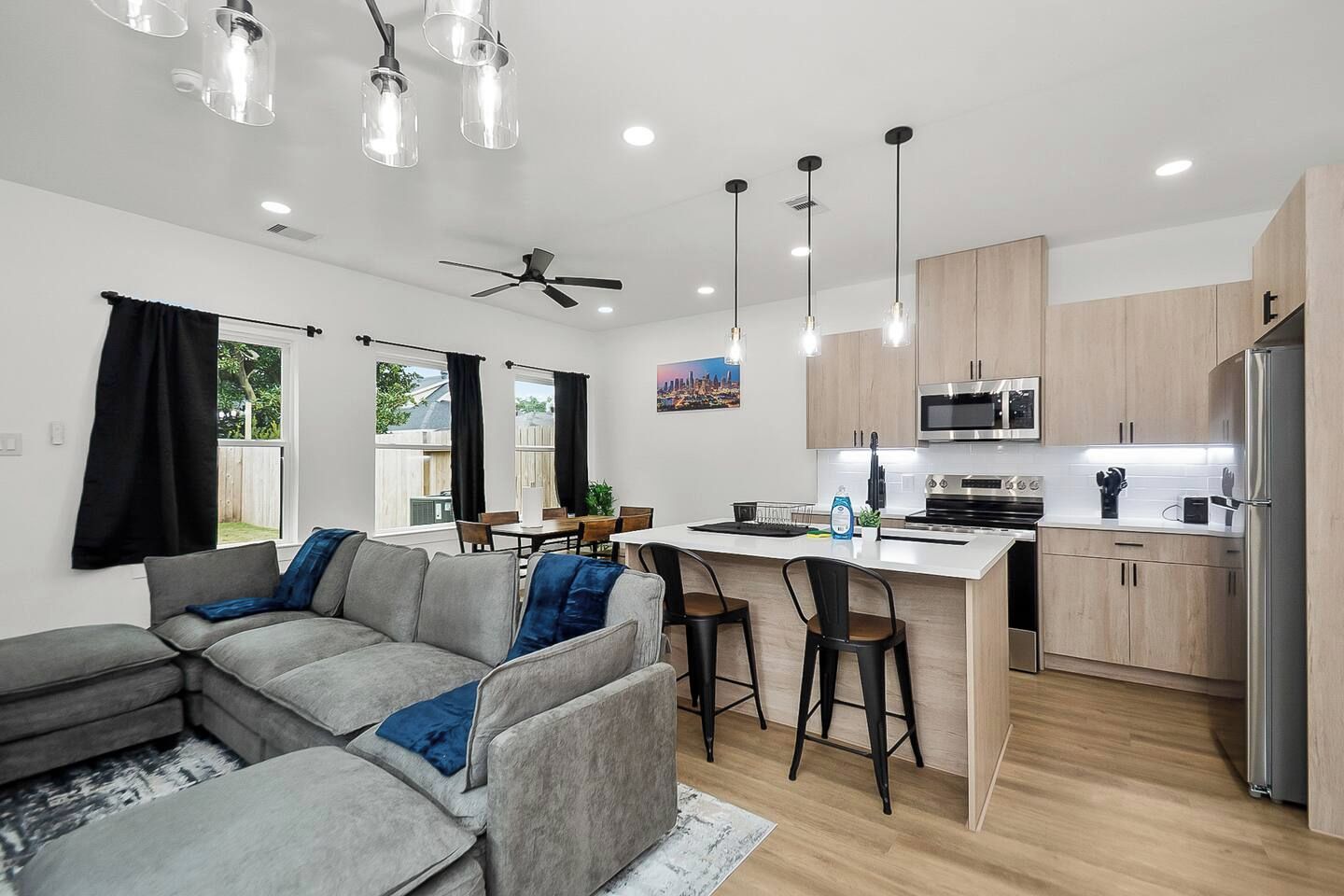 A modern kitchen with a central island, stainless steel appliances, and pendant lighting.