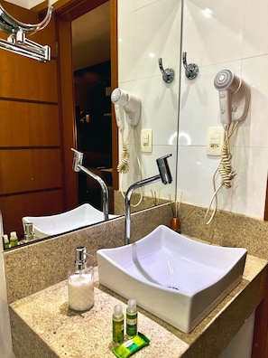 A bathroom with a white sink, a mirror, a hairdryer, and a towel rack.