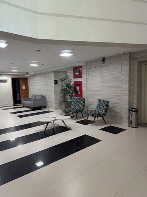 A lobby with a reception desk, seating area, and a trash bin.