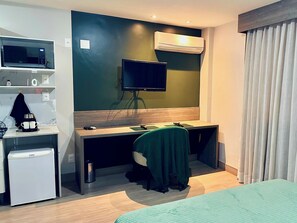 A hotel room with a desk, a television, a microwave, a mini-fridge, and a bed.