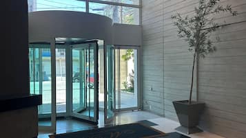 A lobby with a revolving door, a potted plant, and a checkered floor.