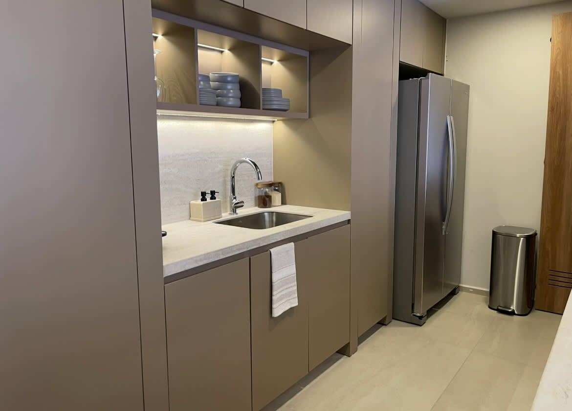 A modern kitchen with a stainless steel refrigerator, a sink, and a trash bin.