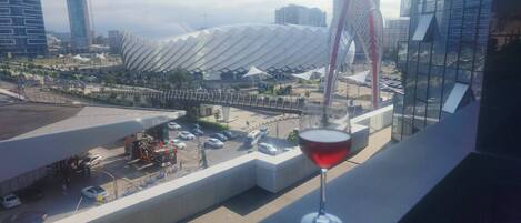 A modern building with a unique curved roof, a parking area, and a glass structure reflecting the cityscape.