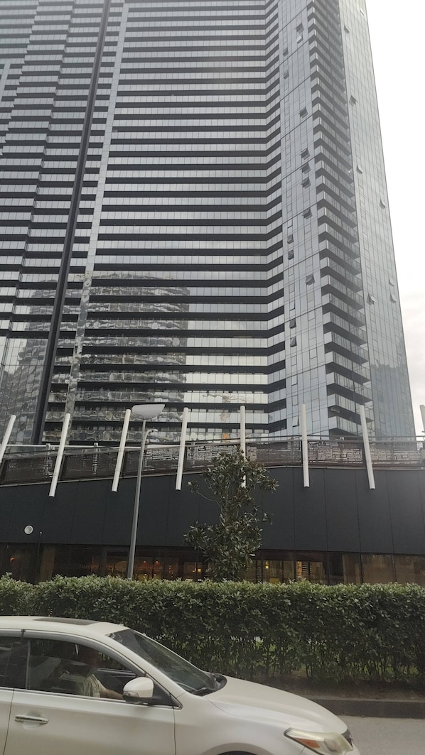 Un immeuble moderne et imposant, doté d’une façade en verre réfléchissant et de plusieurs balcons.
