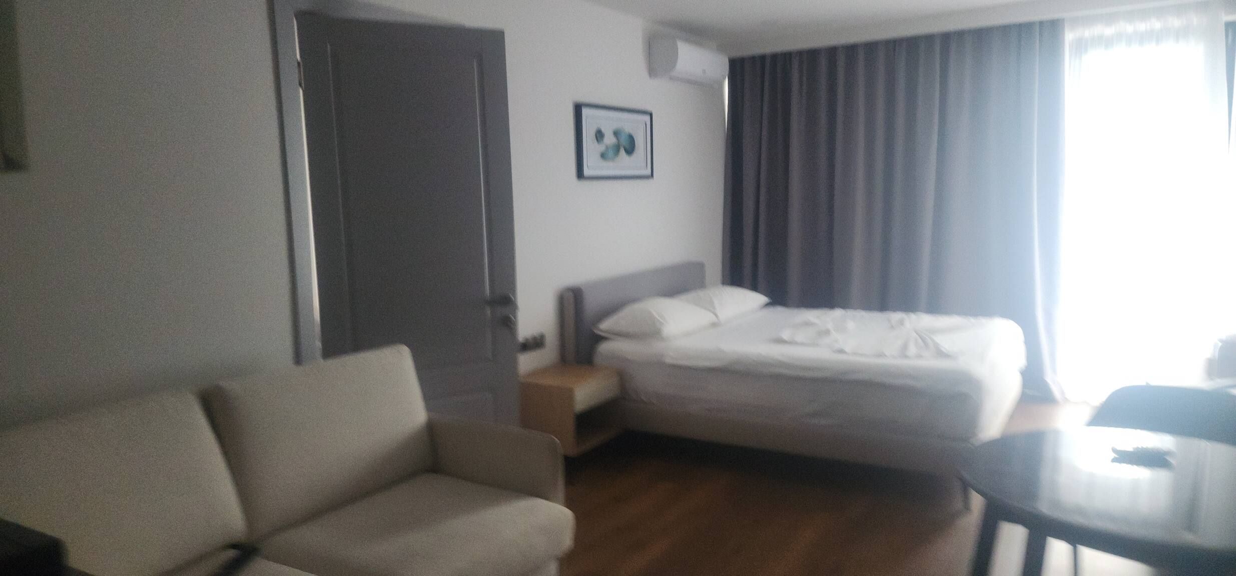 Una habitación de hotel con cama, sofá, una mesita y una puerta.