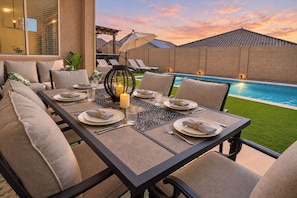 An outdoor dining area with a pool in the background. - Entire home in Goodyear, Arizona, United States (Goodyear)
