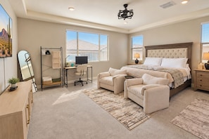 A bedroom with a large bed, a desk, two armchairs, a computer, and a mirror. - Entire home in Goodyear, Arizona, United States (Goodyear)