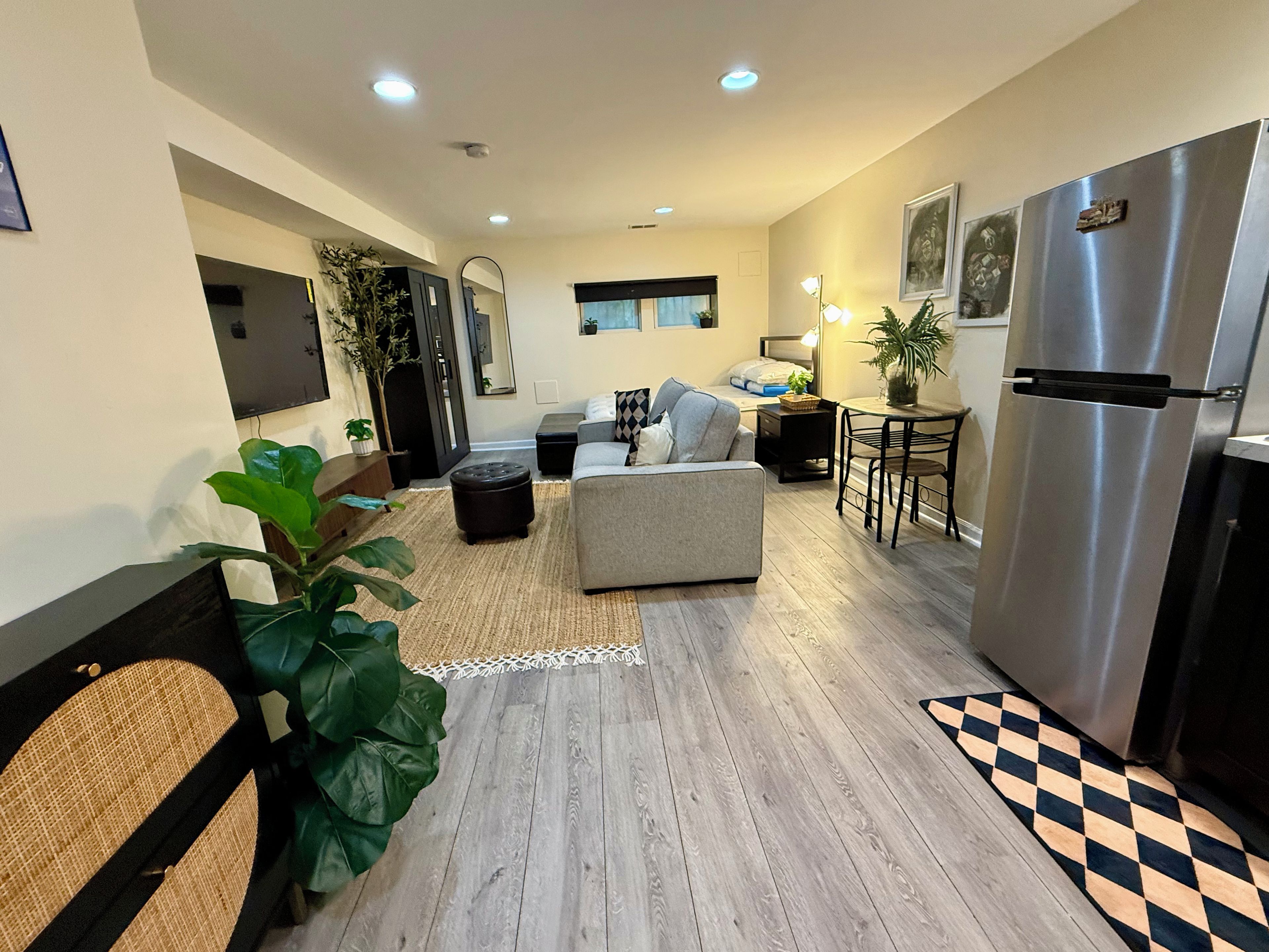 A modern living room with a sofa, ottoman, and a dining area with a table and chairs.
