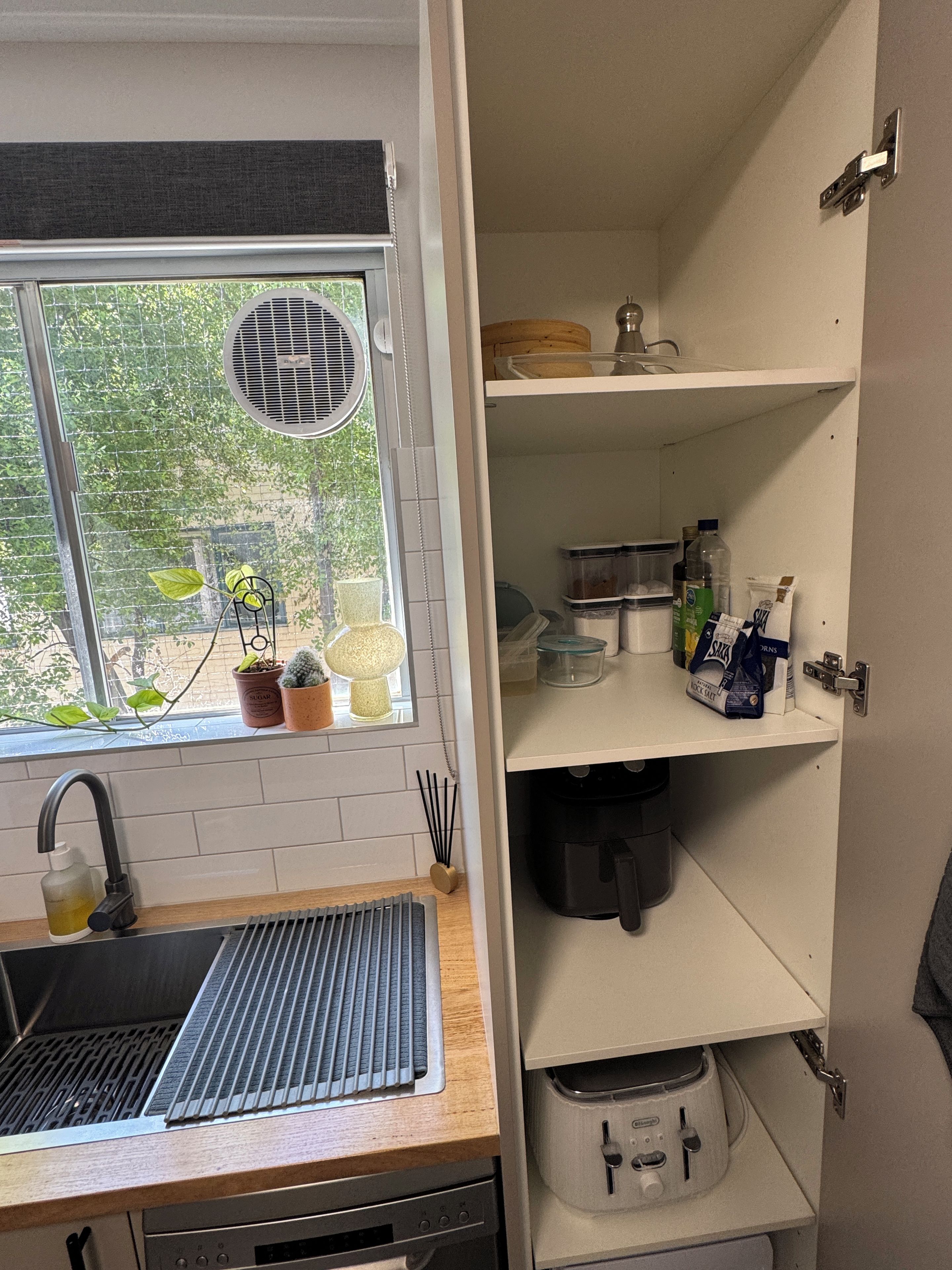 A kitchen with a window, sink, and various storage cabinets.