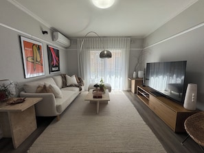 Una sala moderna con sofá, mesa de centro, televisor y obras de arte.
