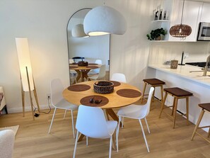Una cocina moderna con una mesa de comedor redonda, sillas blancas y una lámpara colgante.