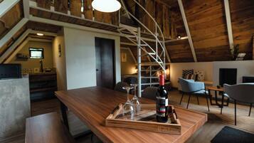 Una mesa de comedor de madera con una botella y vasos, una escalera y un interior moderno.